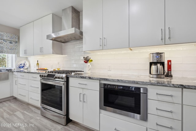 22 Walkers Ridge Dr, Ponte Vedra Beach, FL 32082 - kitchen featuring wall chimney range hood, appliances with stainless steel finishes, light stone counters, white cabinets, and decorative backsplash
