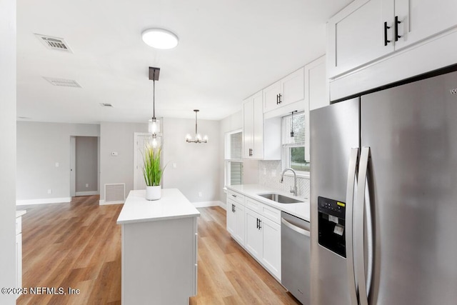 kitchen featuring stainless steel appliances, visible vents, light wood-style flooring, a sink, and a kitchen island