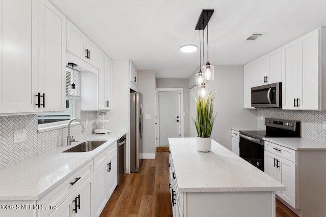 kitchen featuring wood finished floors, a sink, visible vents, appliances with stainless steel finishes, and a center island