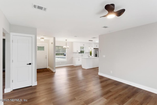 unfurnished living room with wood finished floors, visible vents, and baseboards