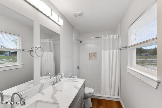 full bath featuring toilet, a sink, visible vents, and a shower stall