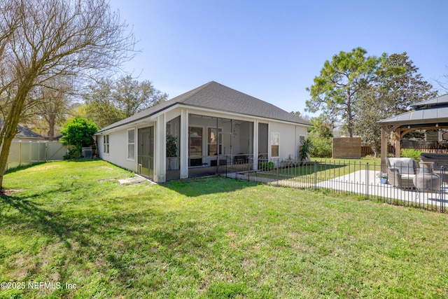 rear view of house with a gazebo, a lawn, a fenced backyard, and a sunroom