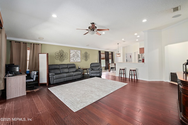 living room featuring crown molding, visible vents, ceiling fan, a textured ceiling, and wood finished floors