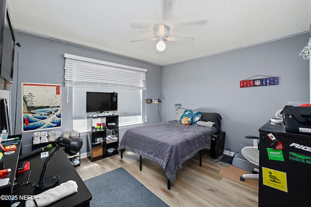 bedroom with a textured ceiling, a ceiling fan, and wood finished floors