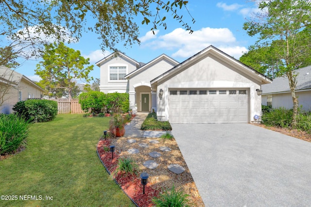 traditional home with a garage, fence, driveway, stucco siding, and a front lawn