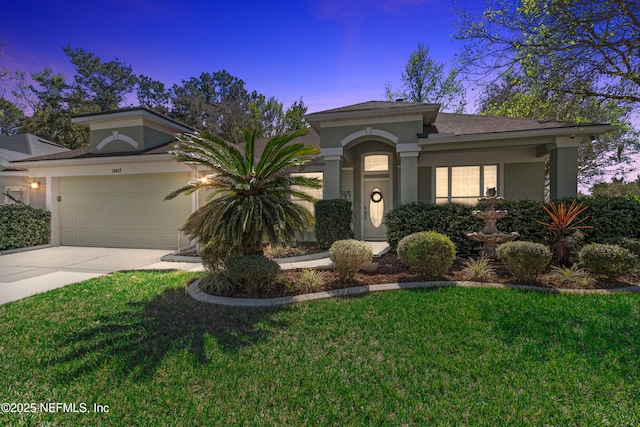 view of front of home featuring stucco siding, an attached garage, concrete driveway, and a yard