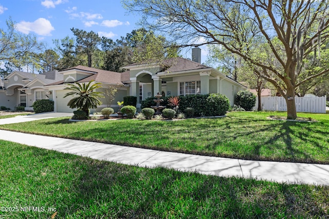 mediterranean / spanish-style house featuring fence, a front yard, stucco siding, a garage, and driveway