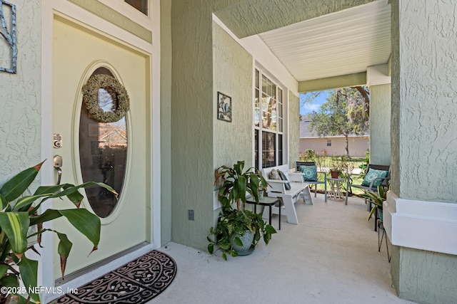 view of exterior entry with stucco siding and covered porch