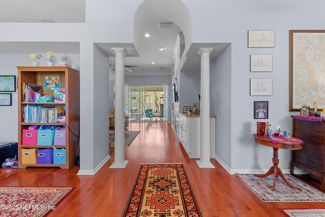 hallway featuring decorative columns, wood finished floors, and baseboards