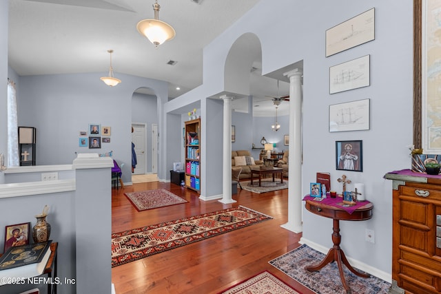 entryway with wood finished floors, baseboards, lofted ceiling, decorative columns, and arched walkways