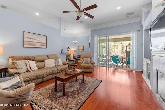 living area with visible vents, recessed lighting, wood-type flooring, crown molding, and a tile fireplace