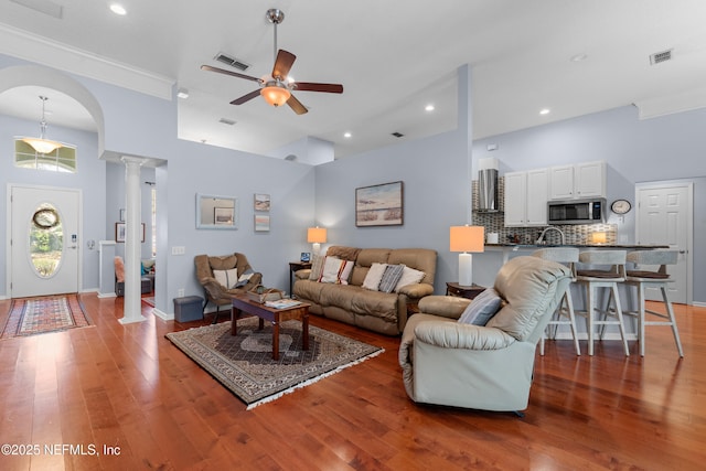 living area featuring hardwood / wood-style floors, visible vents, and ornate columns