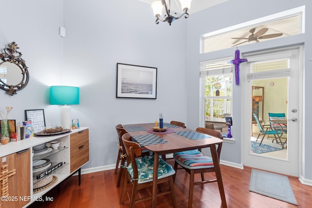 dining area with baseboards, wood finished floors, and ceiling fan with notable chandelier