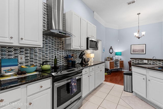 kitchen featuring visible vents, stainless steel appliances, white cabinets, wall chimney range hood, and light tile patterned floors