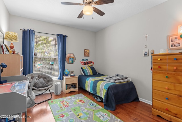 bedroom with ceiling fan, baseboards, and wood finished floors