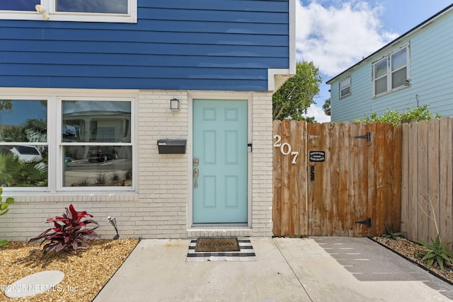 property entrance with fence and brick siding