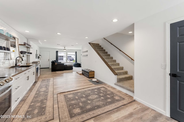 kitchen with a sink, white cabinets, appliances with stainless steel finishes, open shelves, and tasteful backsplash