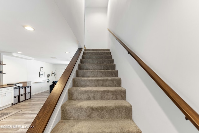 stairway featuring baseboards, wood finished floors, and recessed lighting