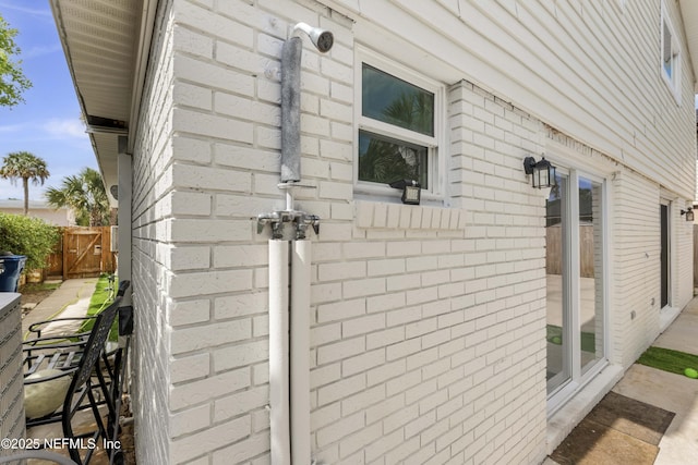 view of side of home featuring brick siding and fence