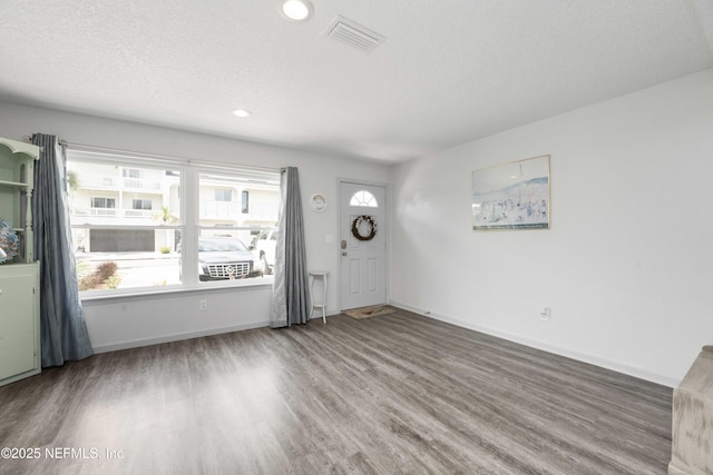 foyer entrance featuring baseboards, visible vents, wood finished floors, a textured ceiling, and recessed lighting