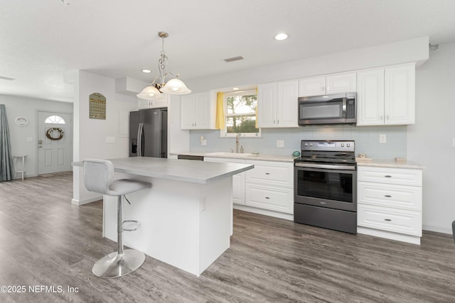 kitchen with stainless steel appliances, light countertops, visible vents, and a center island