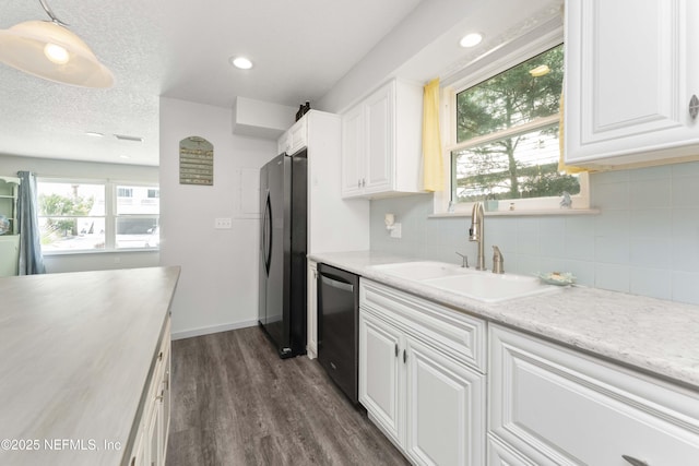 kitchen featuring dark wood-style floors, freestanding refrigerator, stainless steel dishwasher, white cabinetry, and a sink