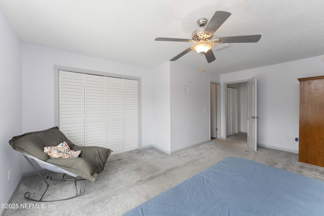 bedroom with baseboards, a ceiling fan, a textured ceiling, carpet flooring, and a closet