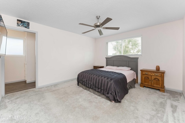 carpeted bedroom featuring a textured ceiling, baseboards, and a ceiling fan