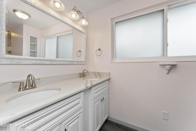 full bathroom with a sink, baseboards, and double vanity