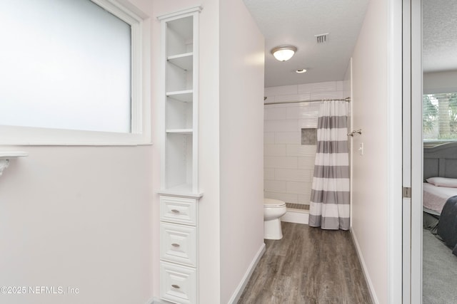 bathroom featuring a textured ceiling, curtained shower, toilet, wood finished floors, and visible vents