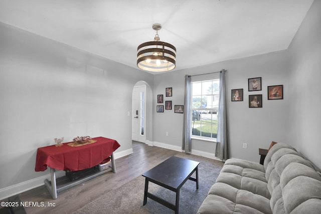 living area featuring baseboards, arched walkways, an inviting chandelier, and wood finished floors