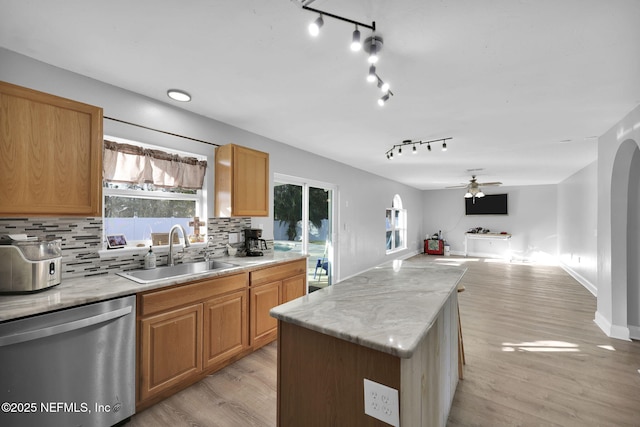 kitchen featuring backsplash, dishwasher, a wealth of natural light, a ceiling fan, and a sink