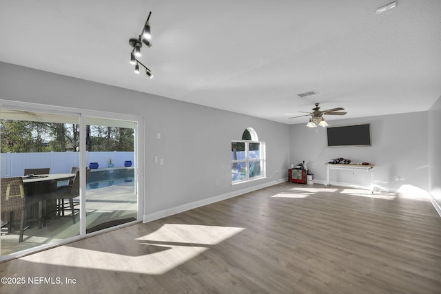 unfurnished living room featuring ceiling fan, visible vents, baseboards, and wood finished floors