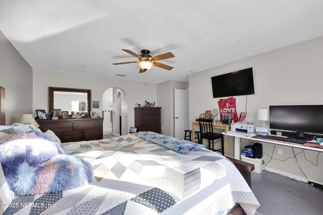 bedroom with visible vents, arched walkways, a textured ceiling, and a ceiling fan