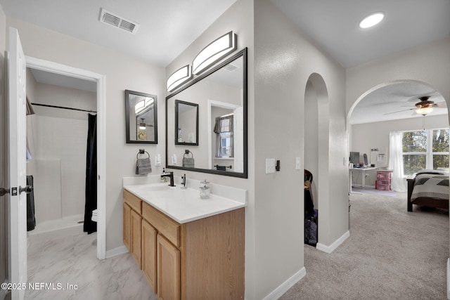 ensuite bathroom featuring vanity, baseboards, visible vents, ceiling fan, and curtained shower