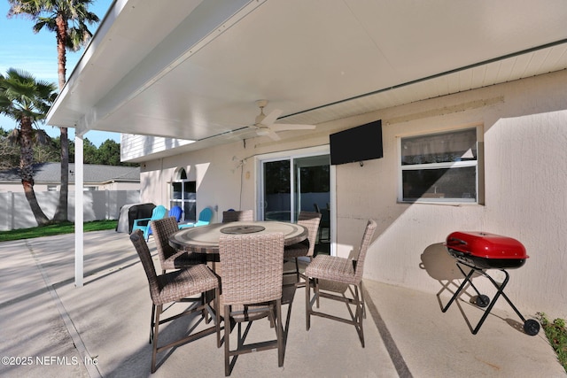 view of patio featuring a grill, outdoor dining space, a ceiling fan, and fence