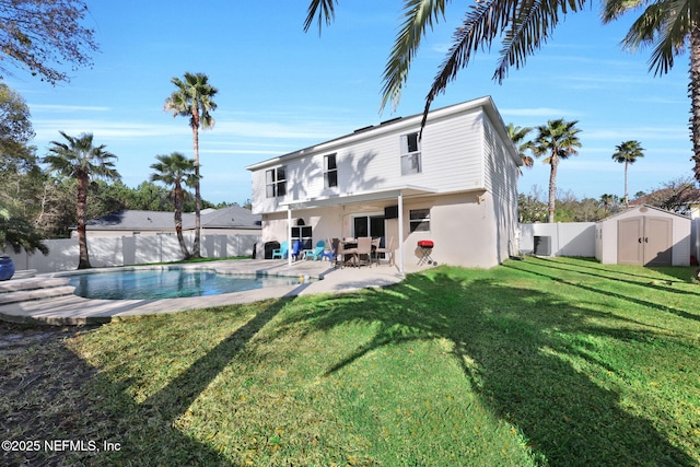 back of property with a shed, a fenced backyard, an outdoor structure, a patio area, and a lawn