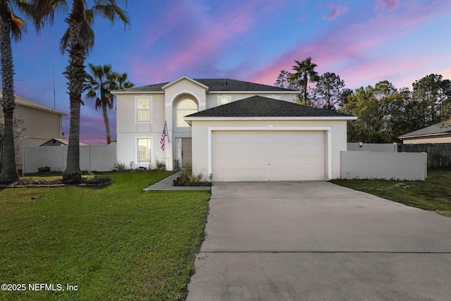 traditional home with stucco siding, concrete driveway, a front lawn, and fence