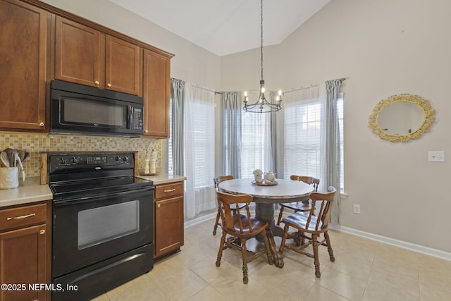 kitchen with lofted ceiling, black appliances, light countertops, decorative backsplash, and baseboards