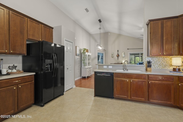 kitchen featuring a sink, black appliances, vaulted ceiling, light countertops, and tasteful backsplash