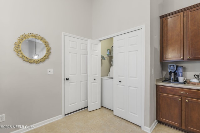 clothes washing area featuring laundry area, light tile patterned floors, baseboards, and washer / dryer