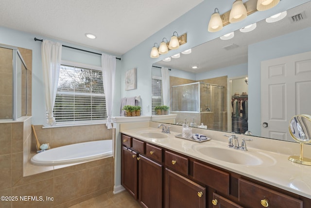 full bathroom with tile patterned floors, visible vents, a stall shower, and a sink