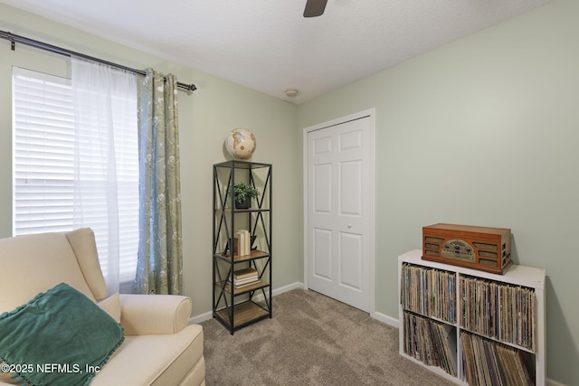 living area with baseboards, carpet floors, a textured ceiling, and ceiling fan