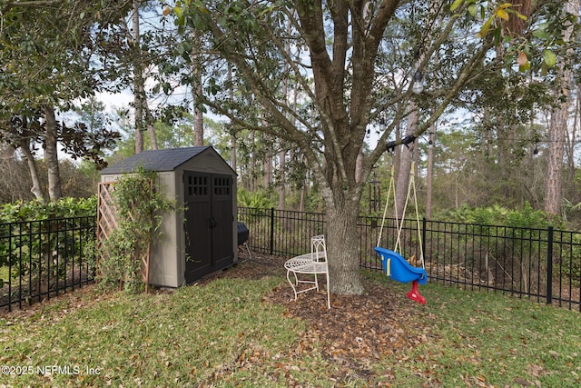 view of yard featuring a storage shed, a playground, a fenced backyard, and an outbuilding