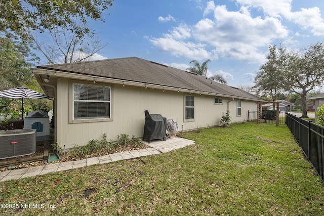 rear view of property with central air condition unit, a yard, and a fenced backyard