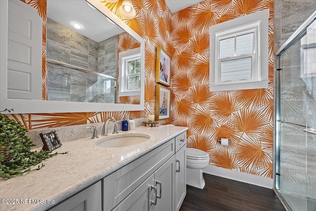 full bathroom featuring a shower stall, baseboards, toilet, wood finished floors, and vanity