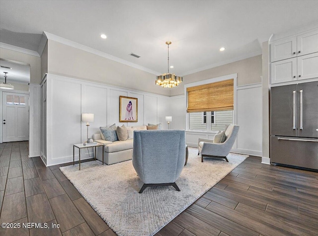 living room featuring visible vents, a notable chandelier, ornamental molding, a decorative wall, and wood tiled floor