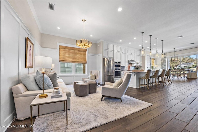 living room featuring a chandelier, recessed lighting, dark wood finished floors, and crown molding