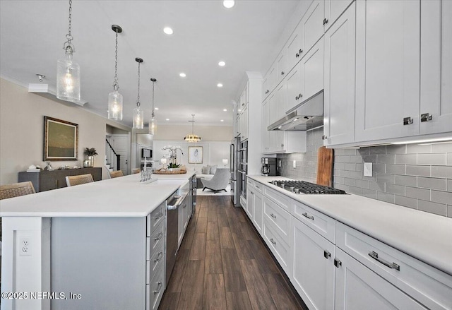 kitchen with under cabinet range hood, open floor plan, dark wood finished floors, and light countertops