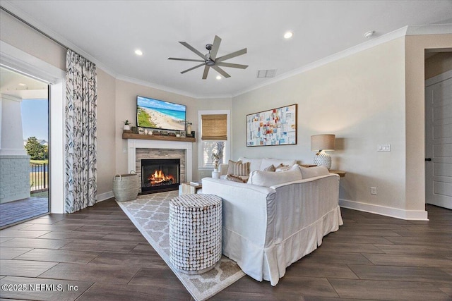 living room with visible vents, a warm lit fireplace, crown molding, and wood finished floors